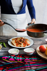 Poster - Mexican woman hands preparing chilaquiles with red sauce and eating traditional mexican food for breakfast in Mexico Latin America, hispanic people