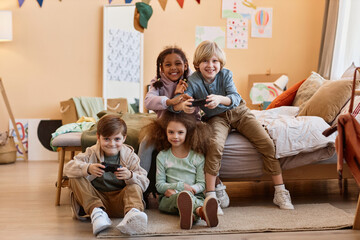 Wall Mural - Full length portrait of diverse group of children playing videogames together and having fun