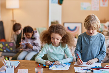 Wall Mural - Waist up portrait of two kids drawing together during art class in after school class, copy space