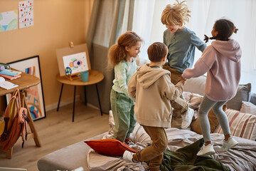 Wall Mural - Group of children jumping on bed together and holding hands, copy space