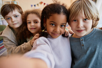 Wall Mural - POV diverse group of happy children taking selfie photo together and smiling at camera