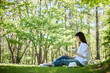 森の中でリラックスしながら読書をする30代日本人女性の初夏のイメージ