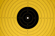 © ninika - close up of a yellow and black target perfectly hit in the center by a bulletin a shooting gallery