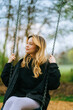 © nikkimeel - Joyful and youthful woman on a swing at the park. Concept pf people and no limit age to play and have fun. Female in outdoors leisure activity using swing and enjoy life