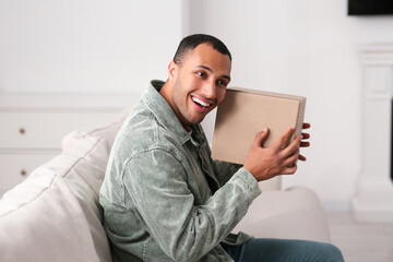 Wall Mural - Happy young man with parcel at home. Internet shopping