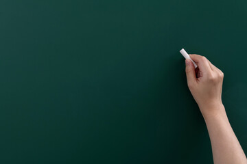 Hand holding chalk writing on chalkboard