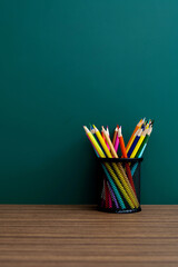 Holder with colorful pencils on classroom table