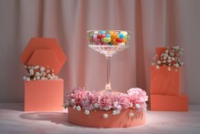 Stylish Presentation Of Glass With Candies, Gypsophila And Carnation Flowers On Pink Marble Table