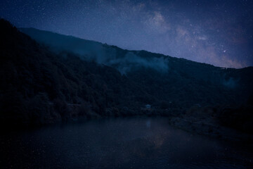 Wall Mural - Lake with reflection of starry sky near mountains. Amazing night landscape