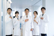 © kapinon - All together image of multiple doctors and researchers all looking at the camera, hands on chest