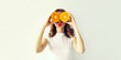 Summer, nutrition, diet and vegetarian concept. Happy healthy cheerful young woman covering her eyes with slices of orange fruits and looking for something on white background