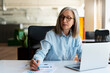 © Maria Vitkovska - Confident serious mature businesswoman using laptop computer, taking notes, working  project in modern office. 60 years old female, financier working with documents at workplace. Successful business