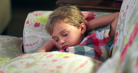 Wall Mural - Toddler boy asleep on sofa at night. Child napping slouched on couch