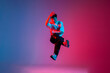 male dancer jumps and flies in the air, young guy hiphop performer break dances in neon club lighting