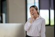 © Wasana - businesswoman covered her mouth to yawn as exhausted from working in office.