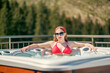 A young girl in red swimsuit and sunglasses relaxing in a jacuzzi.