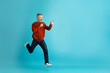 © Prostock-studio - Excited middle aged man running towards copy space on blue