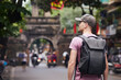 Traveler walking on busy asian street. Rear view of man with backpack in Old Quarter in Hanoi, Vietnam. .
