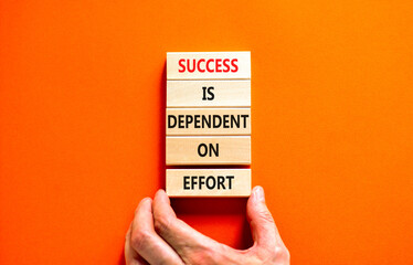 Wall Mural - Success and effort symbol. Concept words Success is dependent on effort on wooden block. Beautiful orange table orange background. Businessman hand. Business success and effort concept. Copy space.