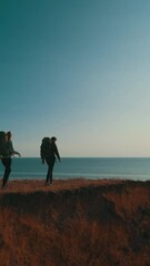 Wall Mural - the couple of tourists walking on the mountain top against sunset background