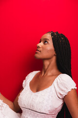 Wall Mural - Beautiful young black woman sitting and serene wearing white outfit with long braids in her hair.