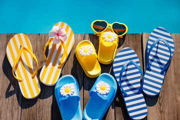 Wall Mural - Beach flip-flops and sunglasses on wooden planks near swimming pool