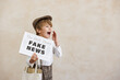 © Sunny studio - Newsboy shouting against grunge wall background. Boy selling fake news