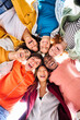 © CarlosBarquero - Vertical large multiracial group of smiling young people standing hugging looking at camera. Group of cheerful people in circle looking down. Low angle view. Copy space.