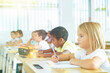 © JackF - Focused cute towheaded preteen schoolgirl writing exercises in workbook in classroom during lesson
