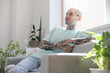 © Pixel-Shot - Young tattooed man sitting on sofa at home