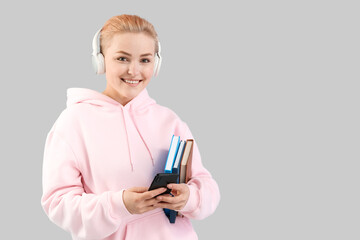 Sticker - Young woman in headphones with books on grey background