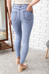 Wall Mural - Young woman in stylish jeans and heeled shoes near mirror in room, back view