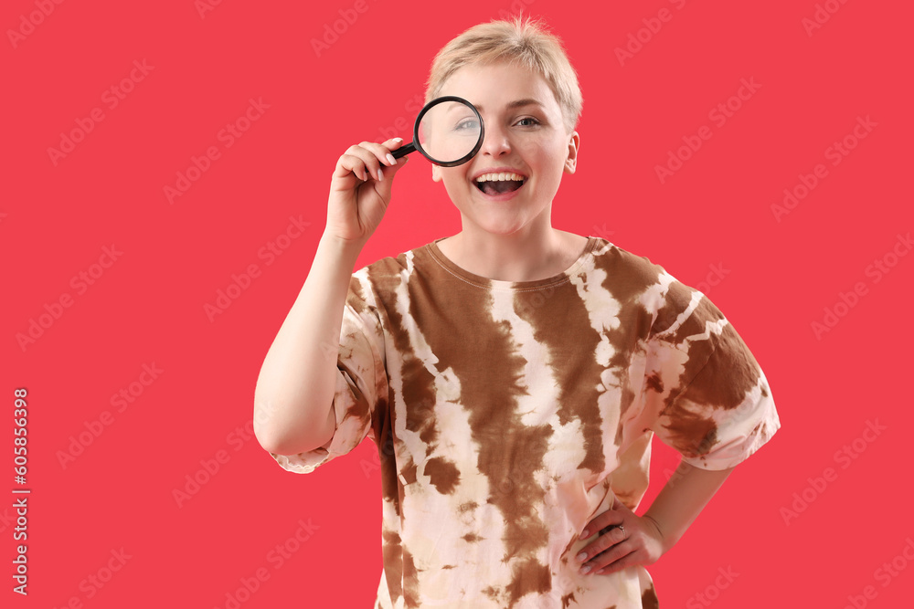 Young woman with magnifier on red background