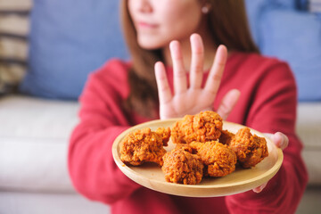 Wall Mural - Closeup of a woman making hand sign to refuse fried chicken for dieting and healthy eating concept