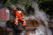© Digital Art Studio - Professional firefighter is sitting on a rusty building holding a water glass and drinking at an outdoor site among the smoke.