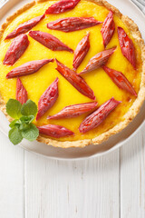 Wall Mural - Crispy shortbread cake with custard and rhubarb close-up in a plate on the table. Vertical top view from above