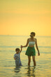 © grooveriderz - Happy family resting at beach in summer, Mother and baby boy feet at the sea foam at the sunlight water is moving