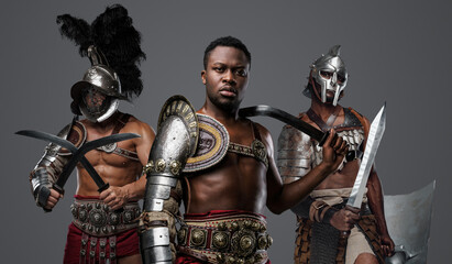 Canvas Print - Portrait of handsome african gladiator from past with paired swords and two comrades.