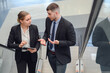 © เลิศลักษณ์ ทิพชัย - A business man and two business women using a digital tablet talking while walking on the escalator business people work together to work at the office
