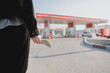 © Mihail - concept of gasoline price increase, vehicle gas station and hand holding money
