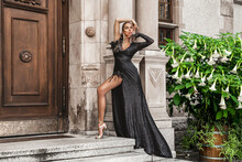 Elegant Luxury Evening Fashion. Glamour, Stylish Elegant Woman In Black Long Evening Gown Dress Is Posing In The City Outdoor. Female Model In Amazing Long Dress. Outdoor Shoot. Vogue. Couture.