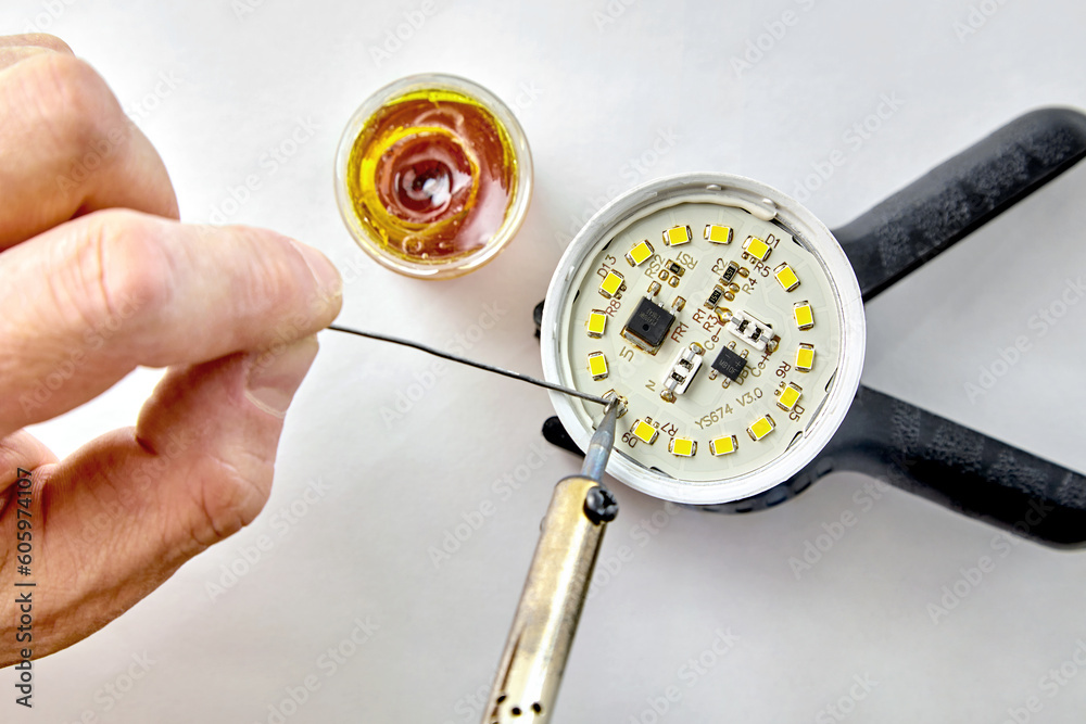 Soldering a burned-out LED into an LED light bulb. Hand with a ...