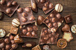 © Jiri Hera - Broken chocolate bars with nuts and pralines on wooden table. Top view.