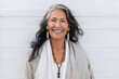 © OPPERMAN - Older woman with grey hair standing in front of a white wall. Generative AI.