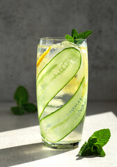 Wall Mural - Cucumber, lemon, mint lemonade. Glass of cool water drink with cucumber, lemon and mint leaves.