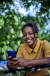 © kerkezz - Smiling young woman with bicycle using mobile phone in city park.