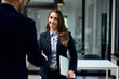 © bnenin - A smiling businesswoman holding a document and handshake with a male colleague.