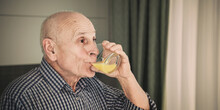 Grandfather Drinking Orange Juice From Glass Close Up Side View. Orange Juice Can Boost Immune System And Help Fight Off Cancer.