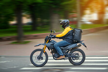 Food Delivery Motor Bike Driver With Backpack Behind Back Is On His Way To Deliver Food. Courier On Motorcycle Delivering Food. MOTION BLUR. Shipping Of Goods To Customers From Restaurant. Takeaway