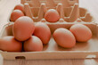 Close up group of organic eggs in brown carton box on wooden background. 